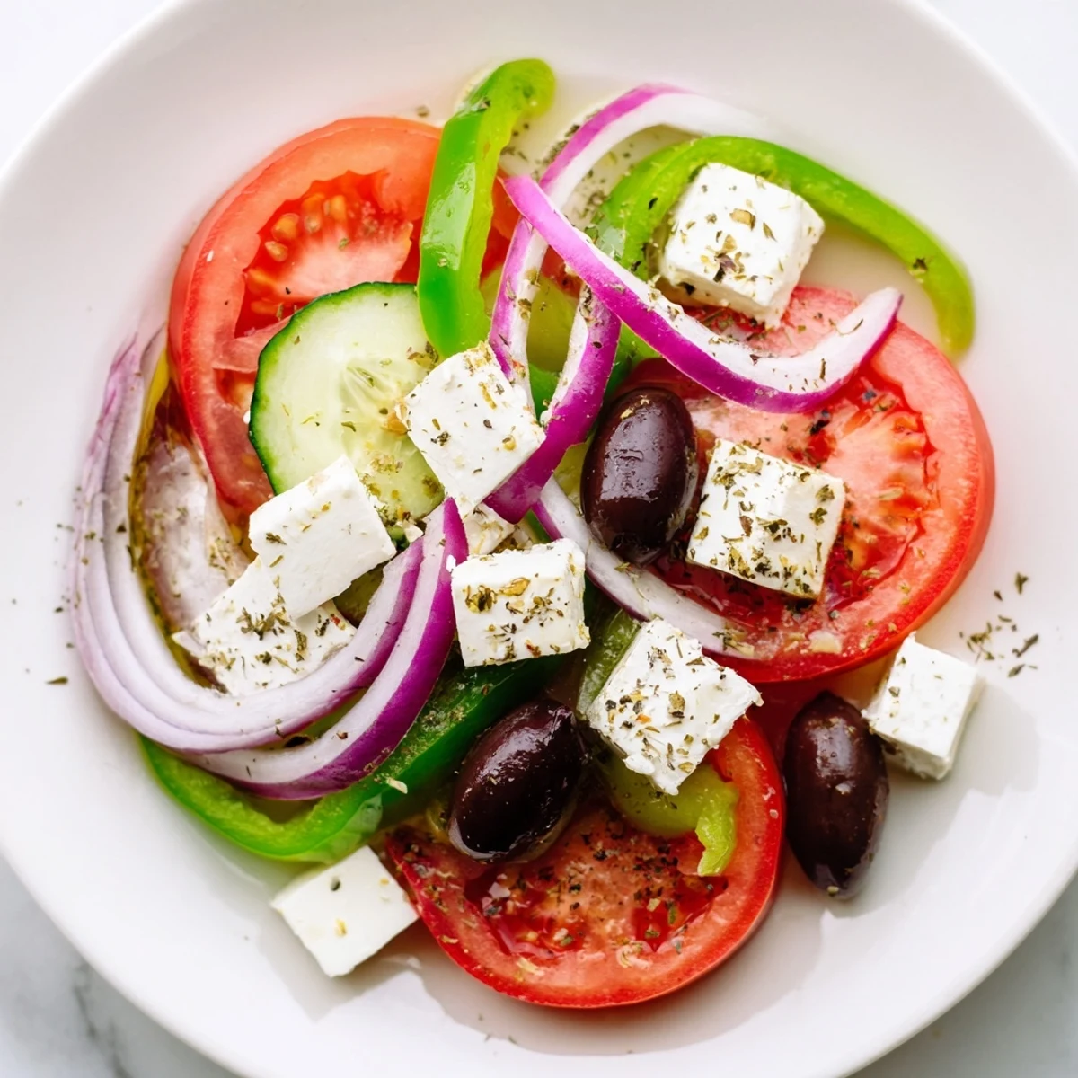 Bright Mediterranean Greek Salad with Kalamata olives and feta on a cutting board, garnished with oregano and drizzled dressing.