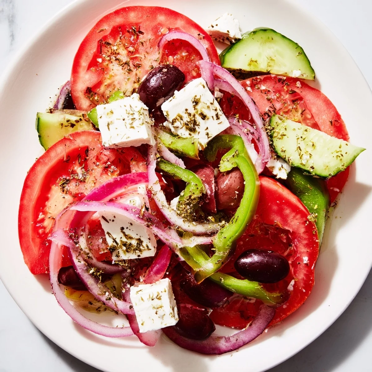 Homemade Greek Salad with Kalamata olives and feta topped with crumbled cheese, sliced veggies, and a balsamic vinaigrette.