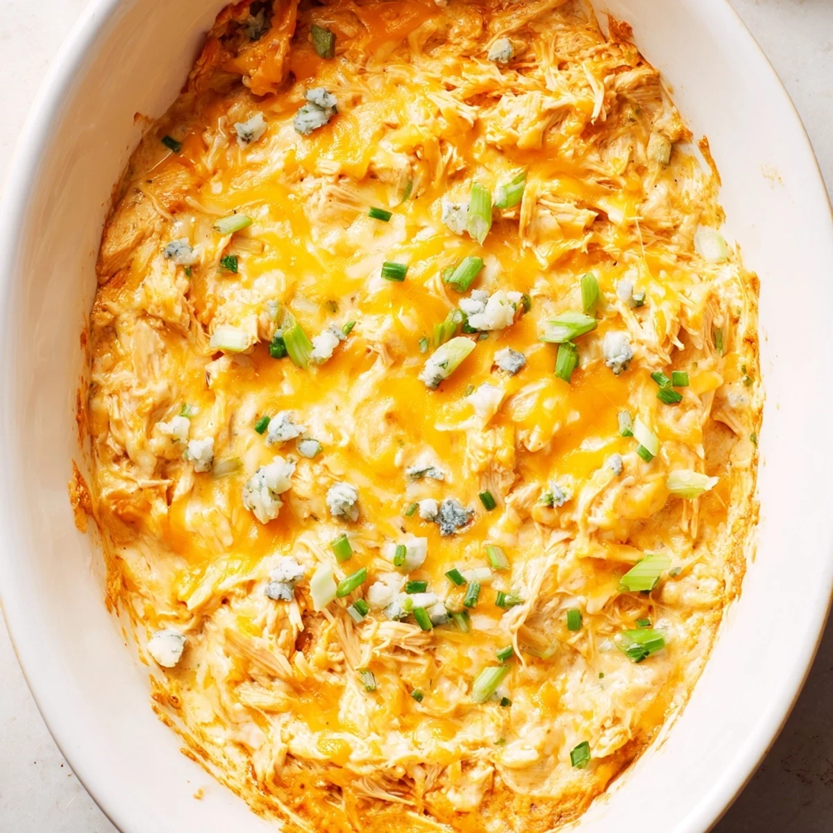 A spoon scoops into the creamy Spicy Buffalo Chicken Dip, revealing shredded chicken and melted cheese inside. 