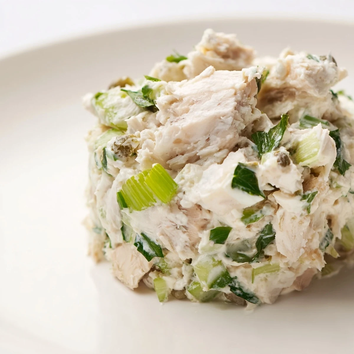 Chilled remoulade sauce with crab meat garnished with celery and pickles, served in a bowl with lemon wedges.