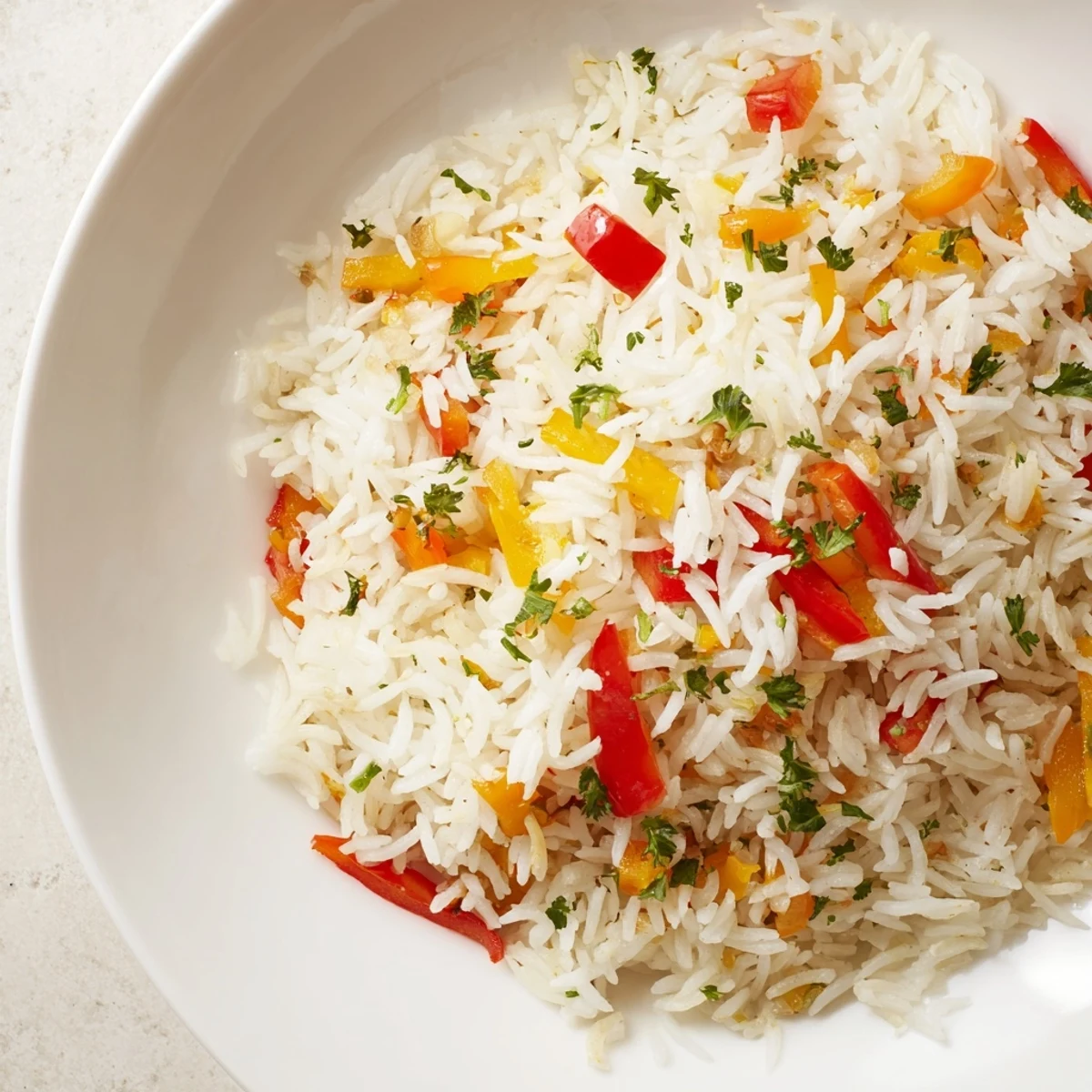 Steamed Rice Pilaf with Peppers and Onions topped with fresh chopped parsley on a white plate.
