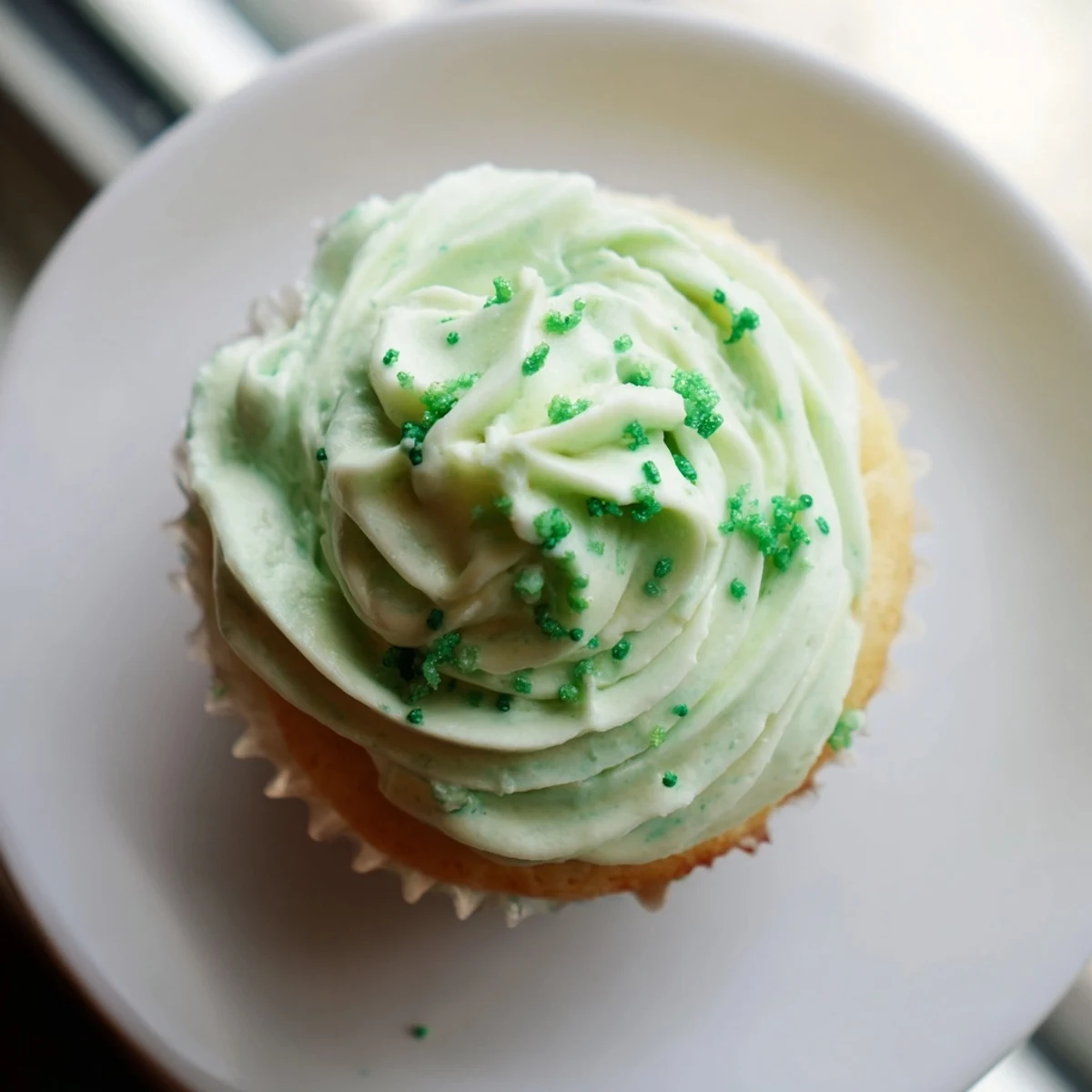 Freshly baked Shamrock Shake Cupcakes with minty green frosting sit on a cooling rack. 