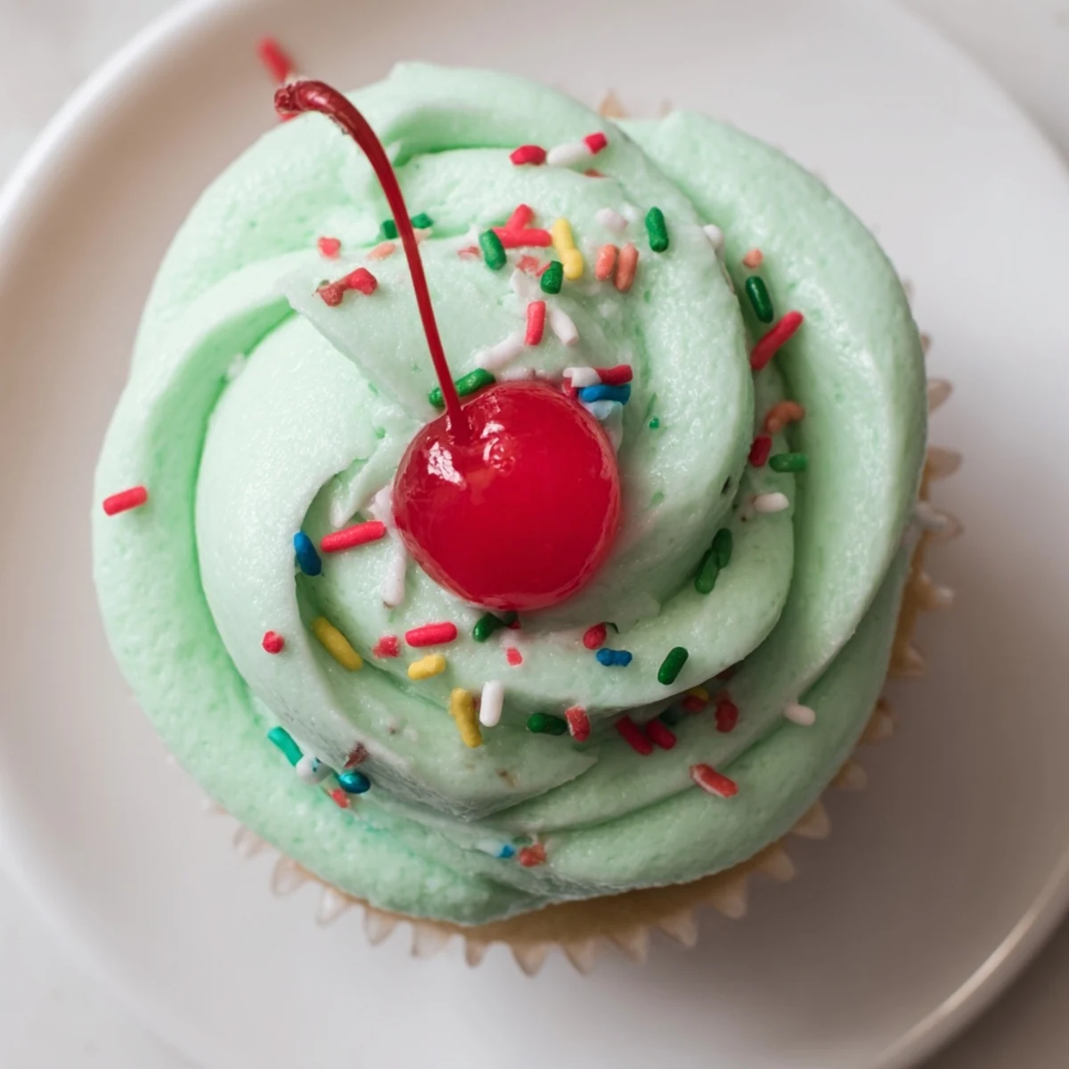 These Shamrock Shake Cupcakes feature creamy mint frosting swirled high on vanilla cupcakes, garnished with a maraschino cherry for a festive, sweet finish.