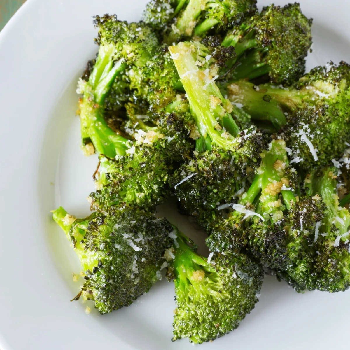 Fresh Roasted Broccoli with Garlic and Parmesan steaming on a plate, topped with grated Parmesan and a squeeze of lemon.