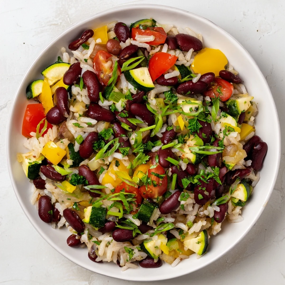 Mardi Gras Veggie Jambalaya with Beans served hot, garnished with fresh parsley and green onions alongside zesty lemon wedges for squeezing.