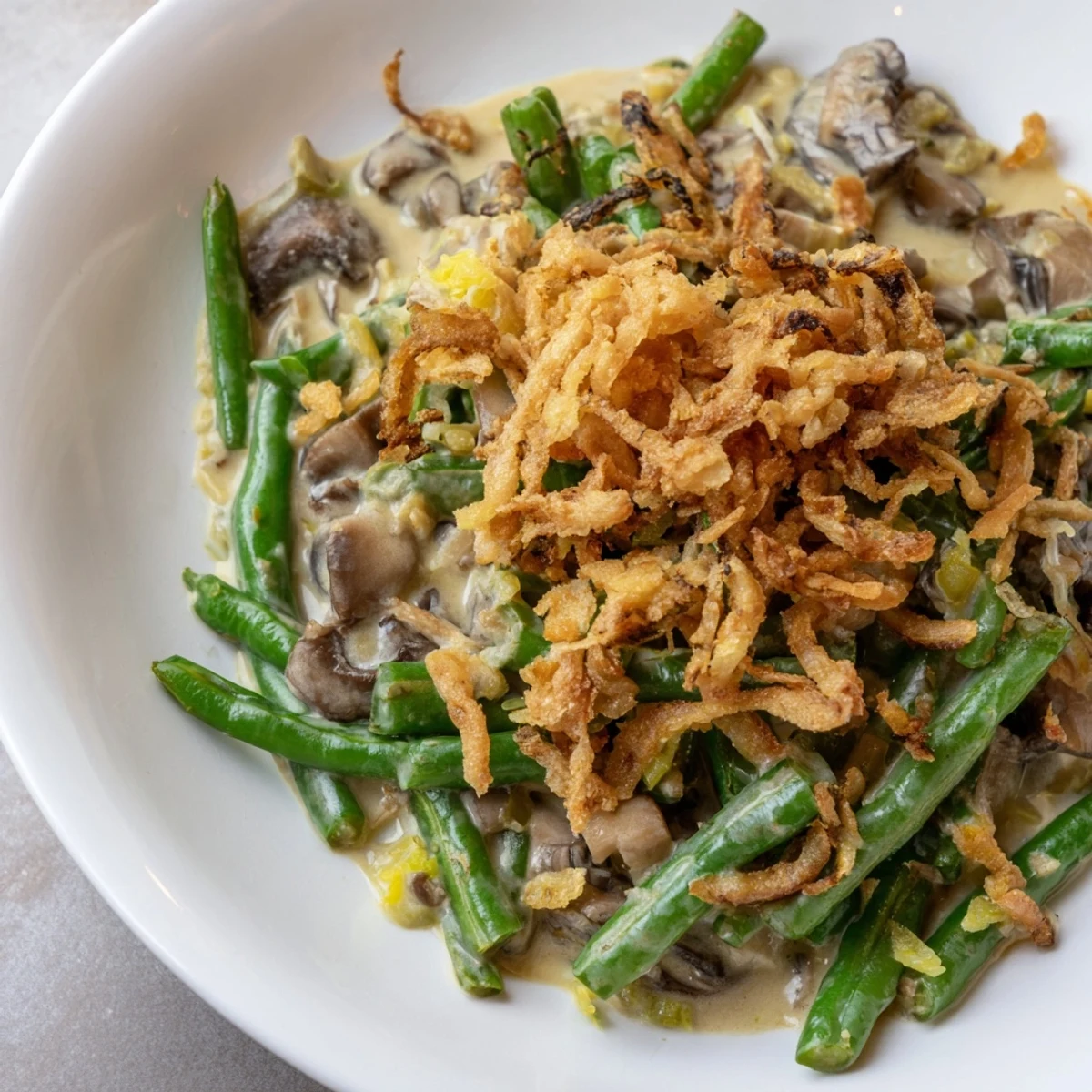 A close up of Green Bean Casserole with Crispy Onions served in a white dish, perfect holiday side dish idea.