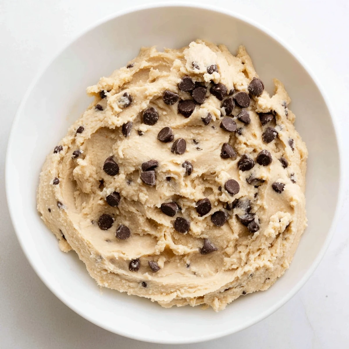 A chilled scoop of Edible Keto Cookie Dough rests on parchment with a keto-friendly serving suggestion.