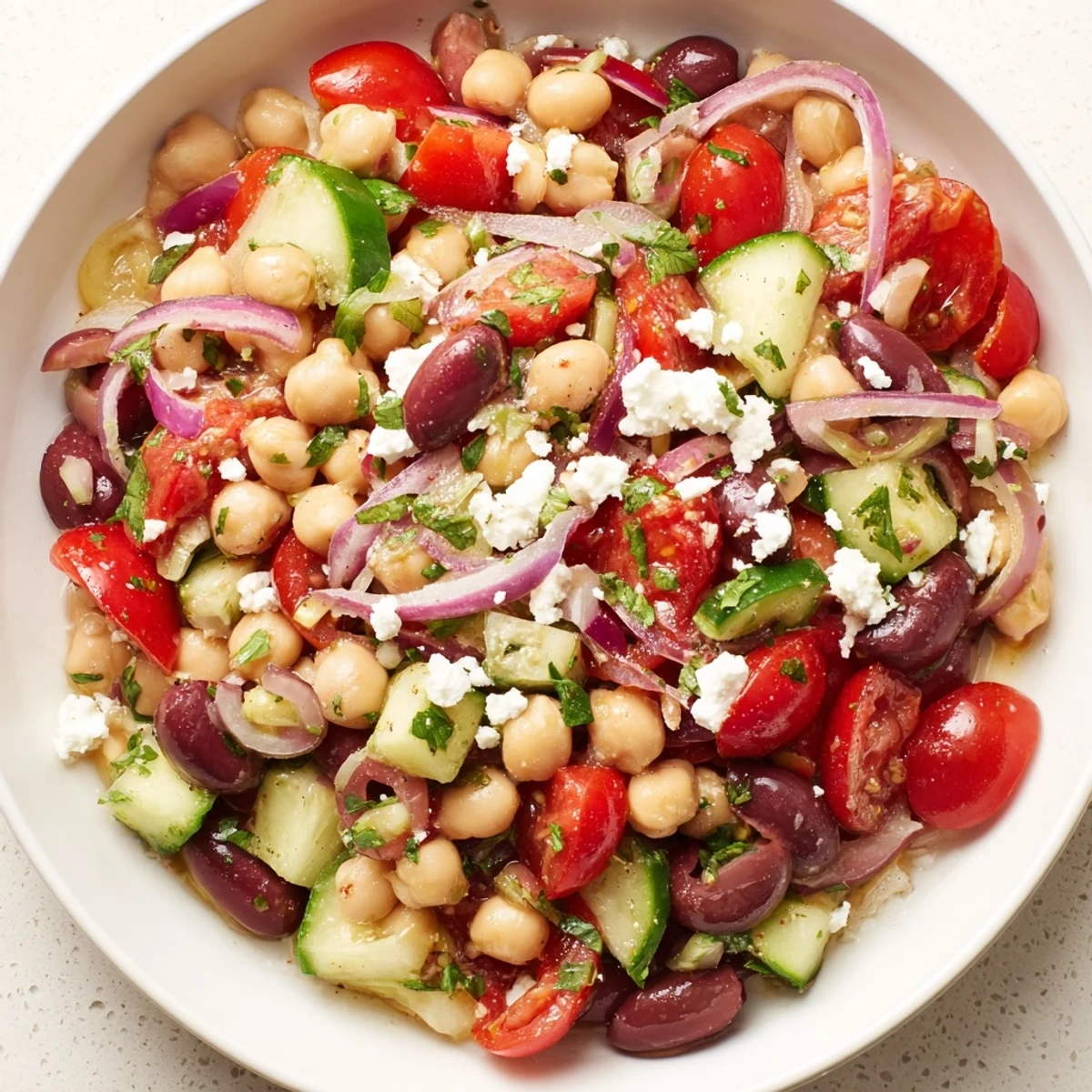 A close-up of Mediterranean Dense Bean Salad with chickpeas, cucumbers, and feta in a rustic bowl.