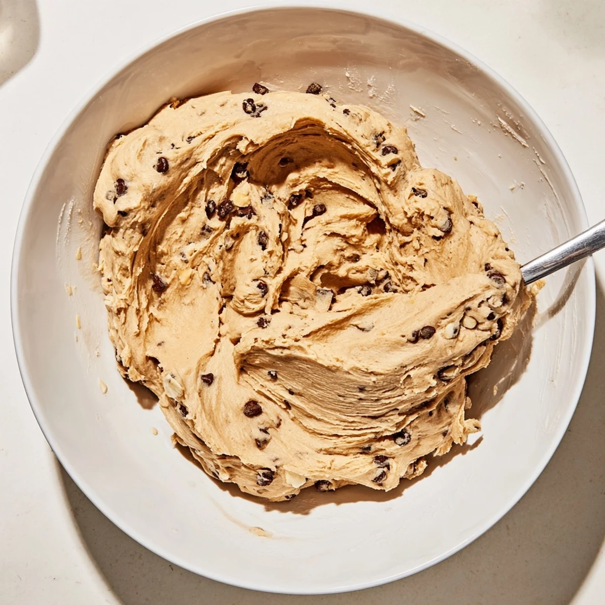 This bowl of Chocolate Chip Greek Yogurt Cookie Dough is ready to eat with a spoon, garnished with chocolate chips.