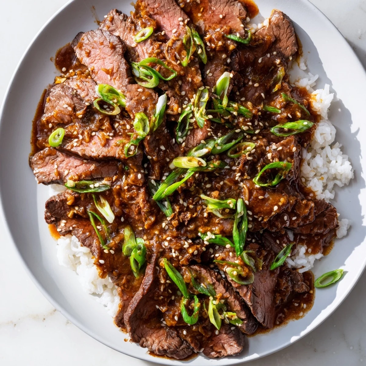 Steaming Ultimate Slow Cooker Mongolian Beef with green onions and sesame seeds on white rice.  