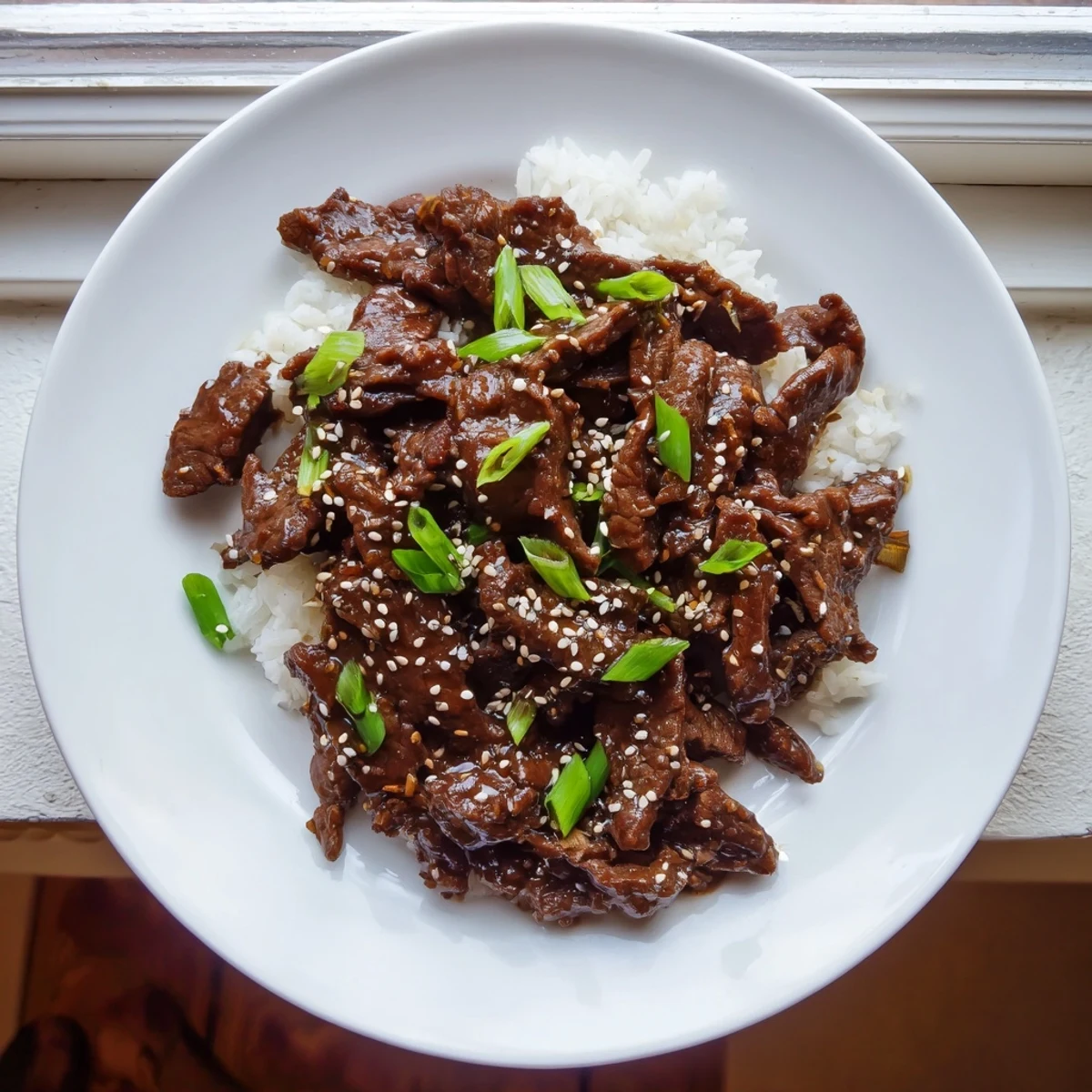 Ultimate Slow Cooker Mongolian Beef glazed in savory-sweet sauce with tender beef strips and sesame seeds.  