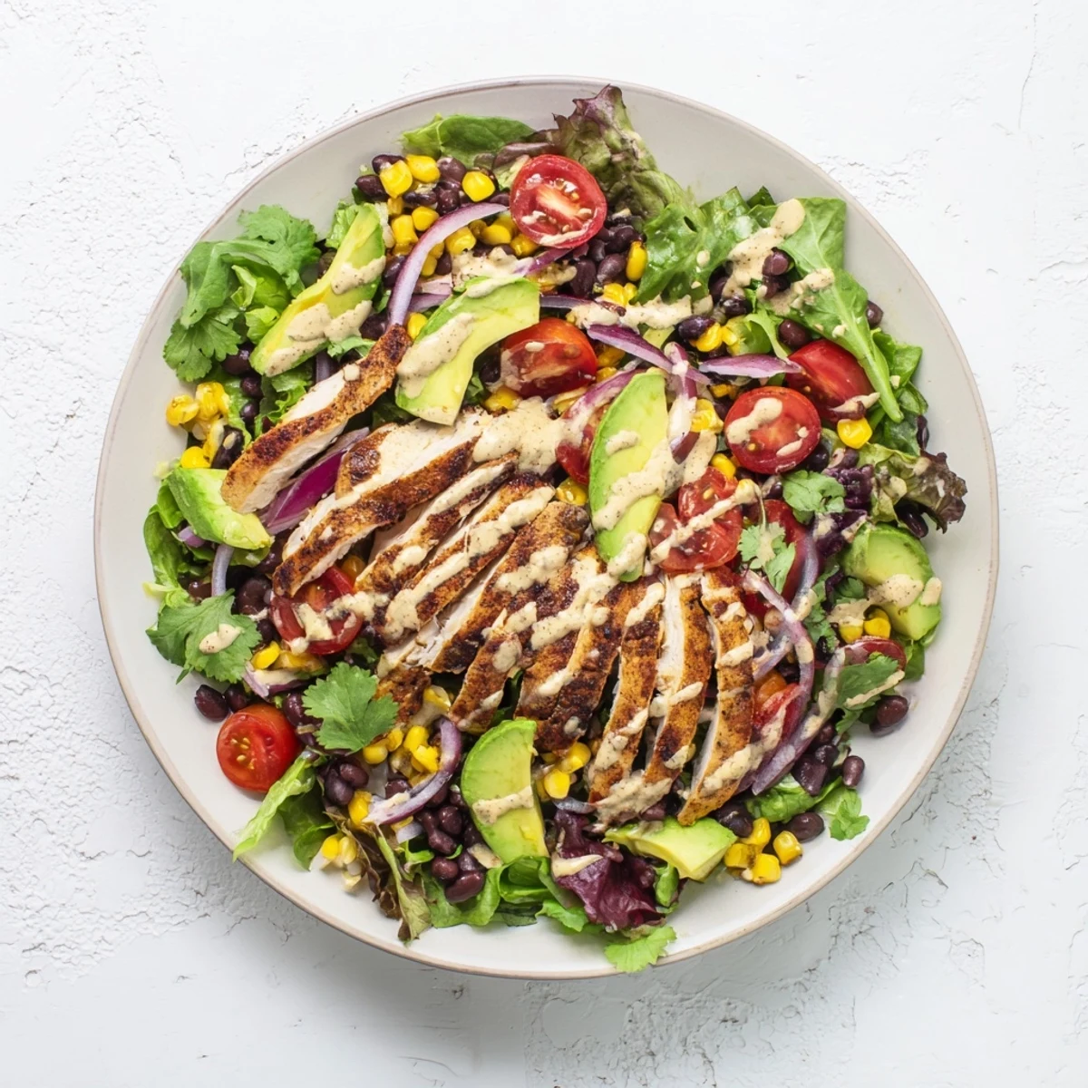 Sliced smoky chipotle lime chicken rests atop a bed of crisp mixed greens, cherry tomatoes, avocado, and black beans, drizzled with zesty lime dressing for a refreshing Mexican-inspired main dish.