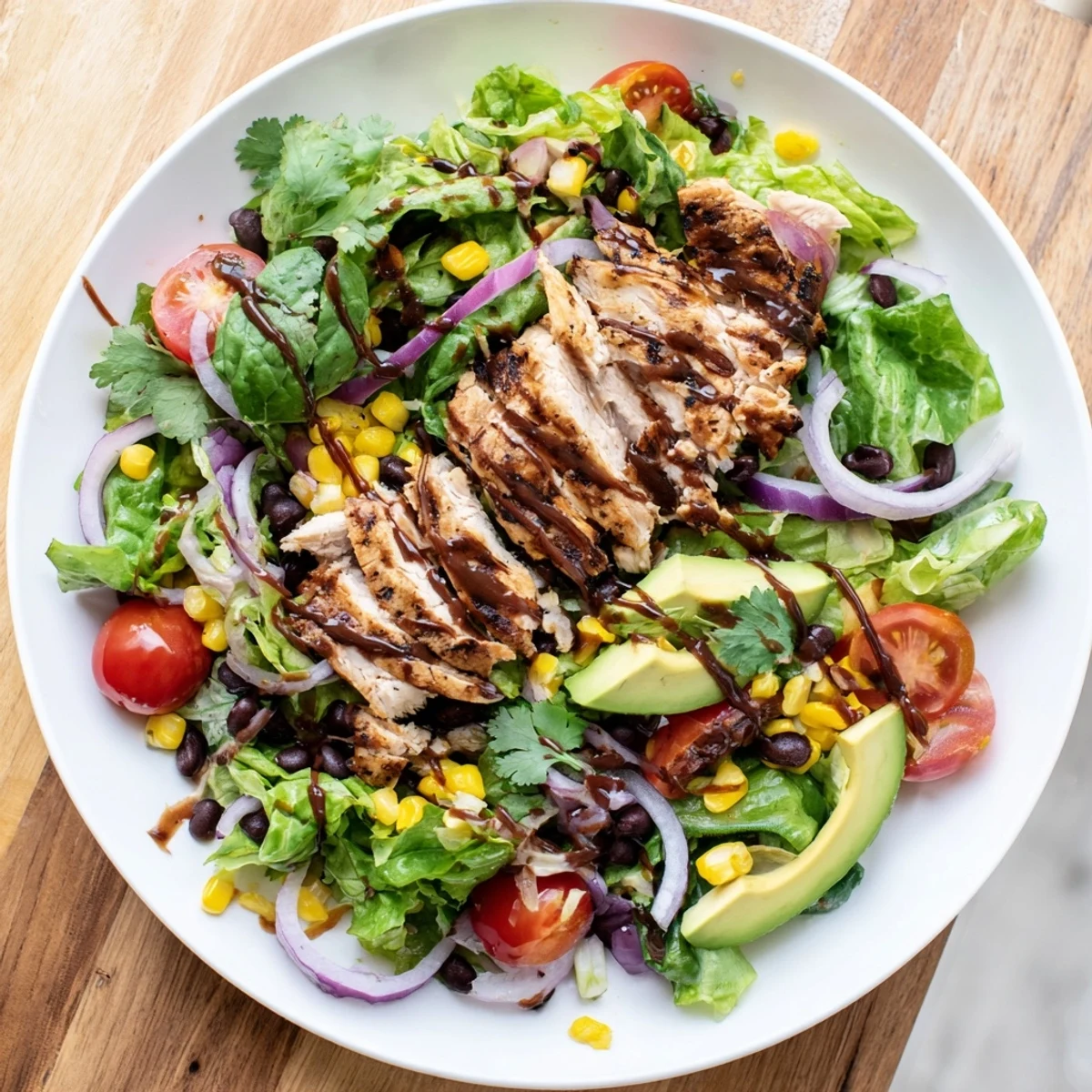 A vibrant bowl of chipotle lime chicken salad showcases grilled chicken slices over fresh romaine, corn, and red onion, with a tangy dressing that highlights the smoky and citrusy flavors.