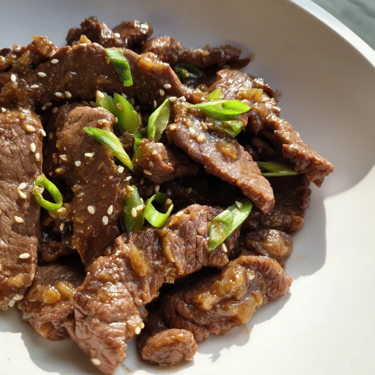 Slow cooker Mongolian Beef with rich, aromatic garlic and ginger sauce, steaming beside a bowl of jasmine rice for a comforting dinner.
