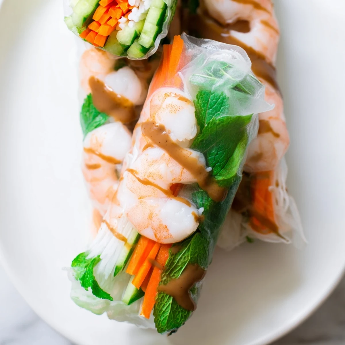 A close-up of Vietnamese Spring Rolls filled with julienned carrots, cucumber, and mint, served with peanut sauce.