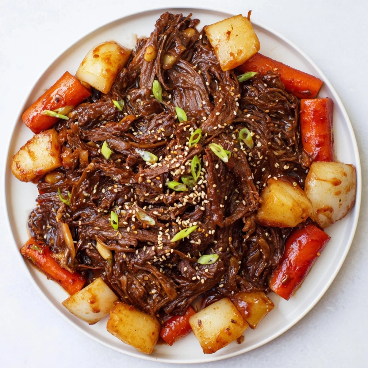Korean Style Pot Roast glistens with a rich, reddish-brown sauce, served over steamed rice with scallions and sesame seeds.