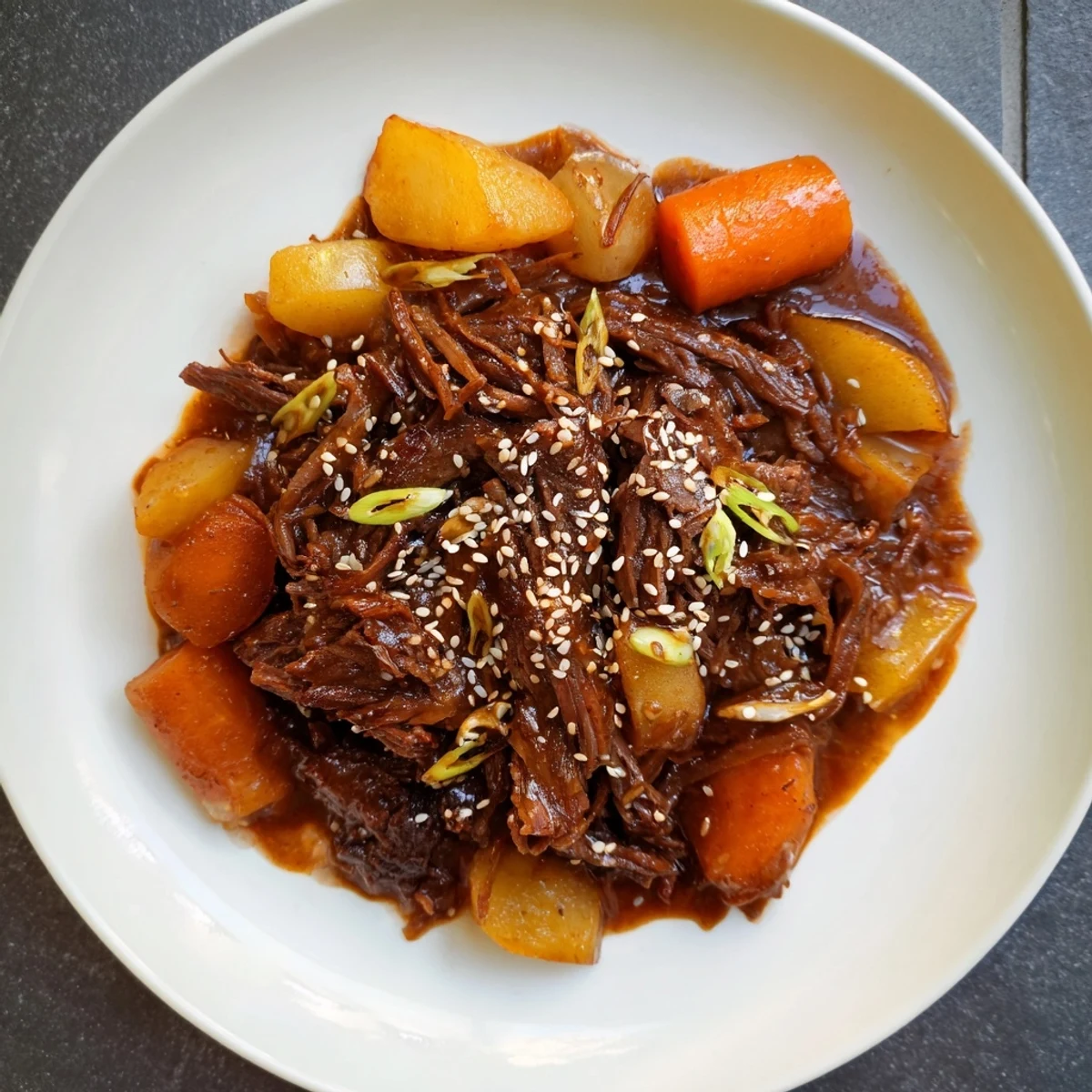 Tender shredded beef in Korean Style Pot Roast sits beside carrots and daikon in a savory-sweet glaze.