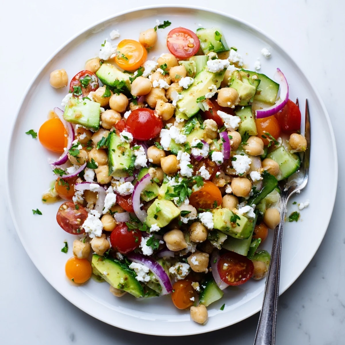 Creamy avocado and tangy feta enrich this vibrant Chickpea Feta Avocado Salad with fresh cucumber and tomato slices.