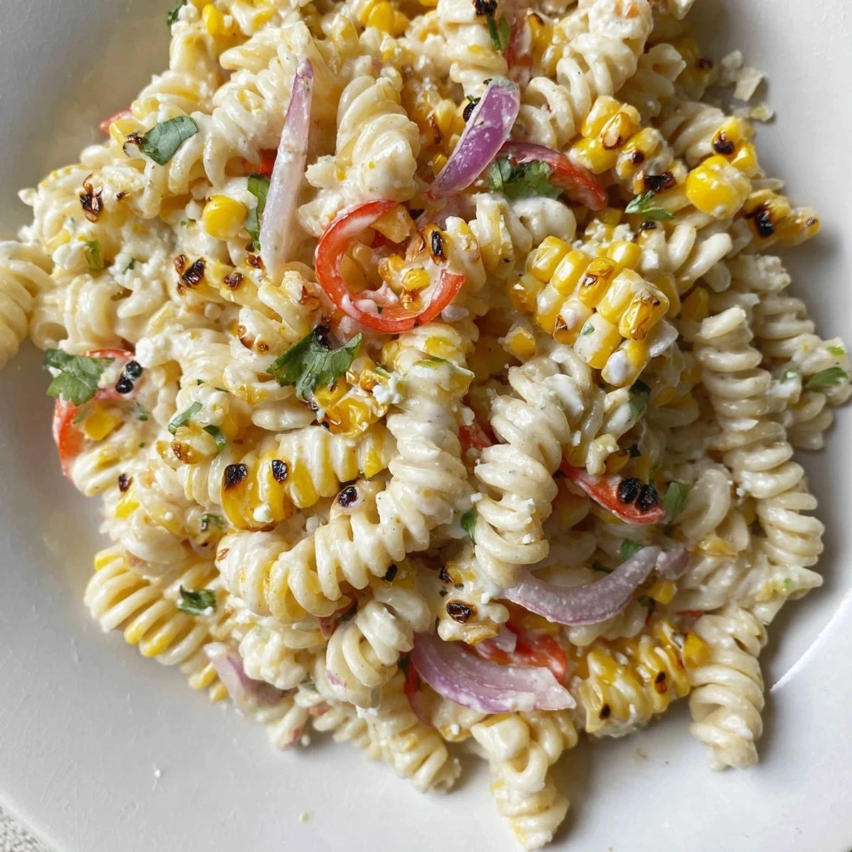 Colorful bowl of juicy street corn pasta salad loaded with sweet corn kernels and creamy dressing