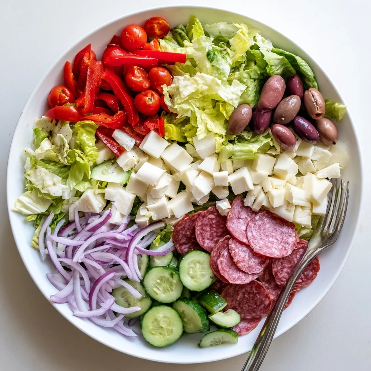 Bountiful bowl of Italian Chopped Salad featuring crunchy vegetables and cured meats drizzled with dressing