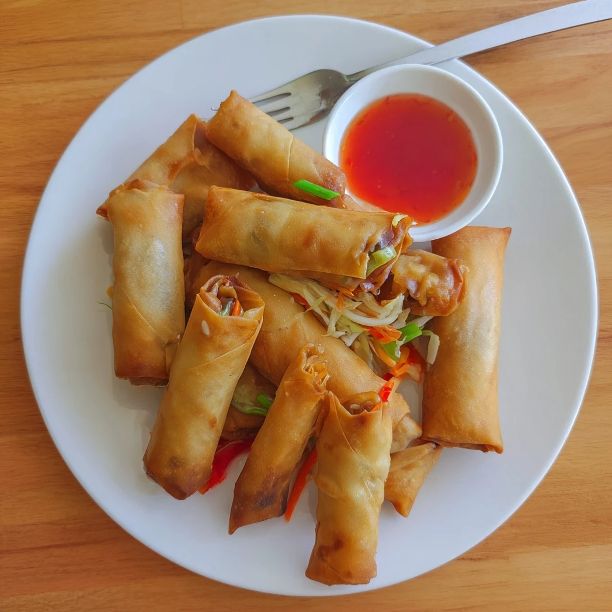 Plate of freshly fried Chinese vegetable spring rolls served with sweet chili sauce for dipping
