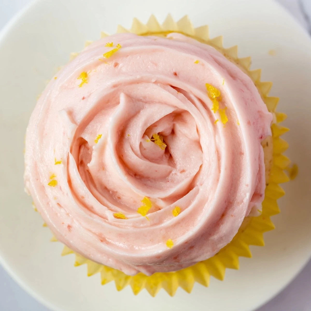 Spring-inspired lemon cupcakes crowned with fluffy strawberry buttercream and citrus zest sprinkles