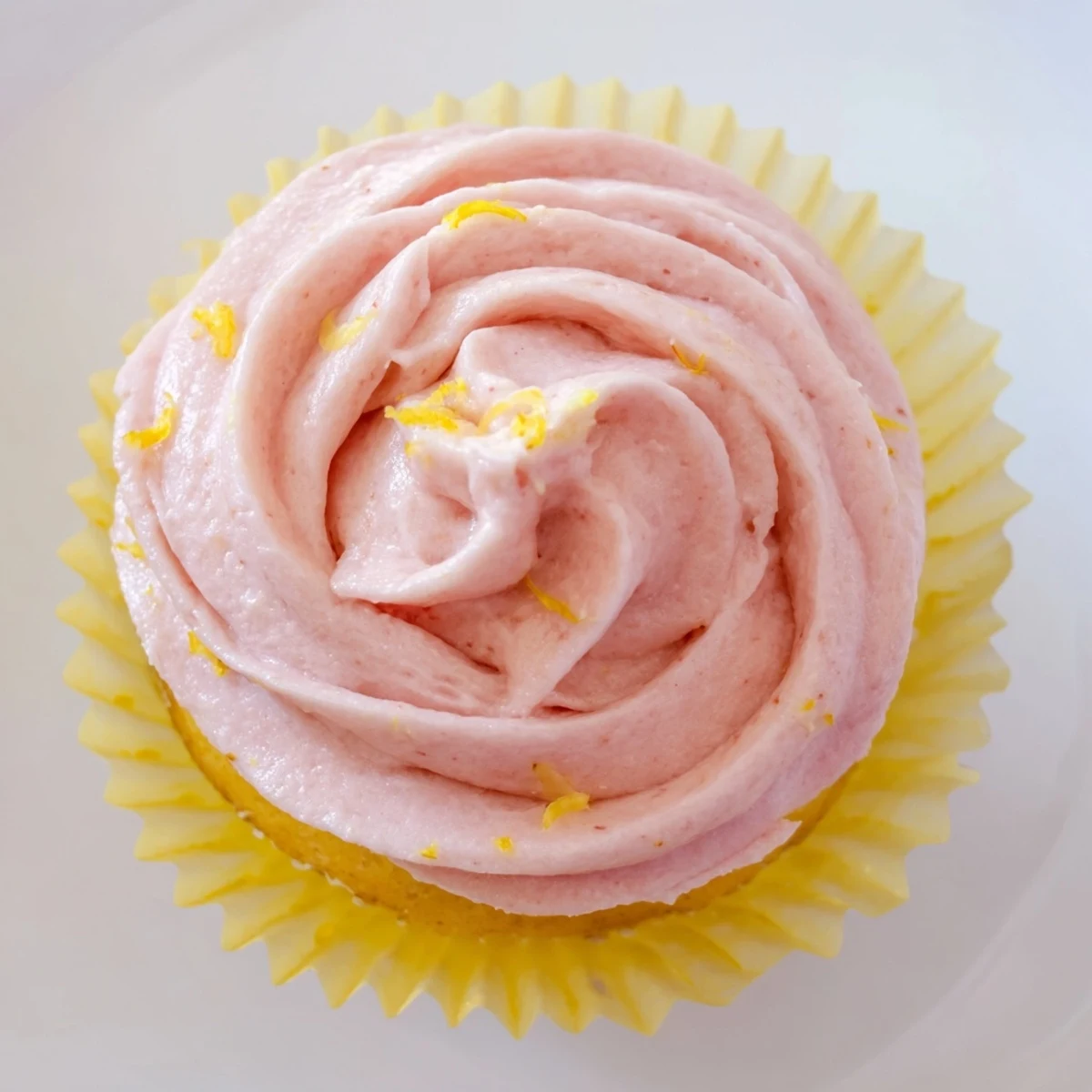 Soft lemon cupcakes topped with naturally pink strawberry frosting and fresh strawberry garnish