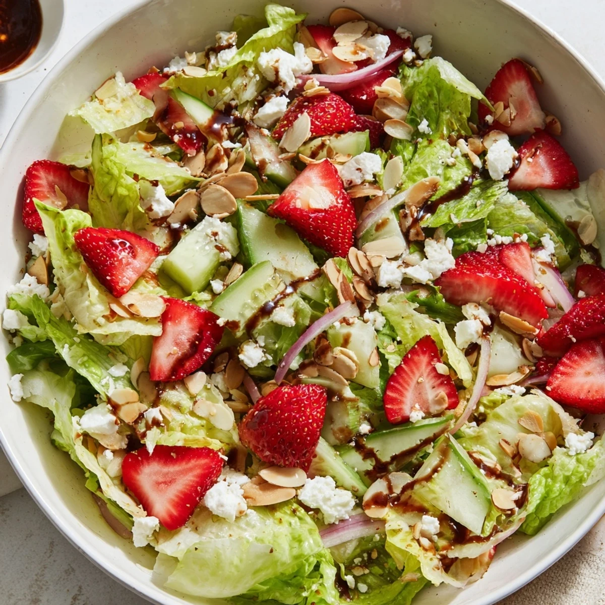 Refreshing strawberry romaine feta salad featuring crisp lettuce, juicy berries, and toasted almonds in a serving bowl