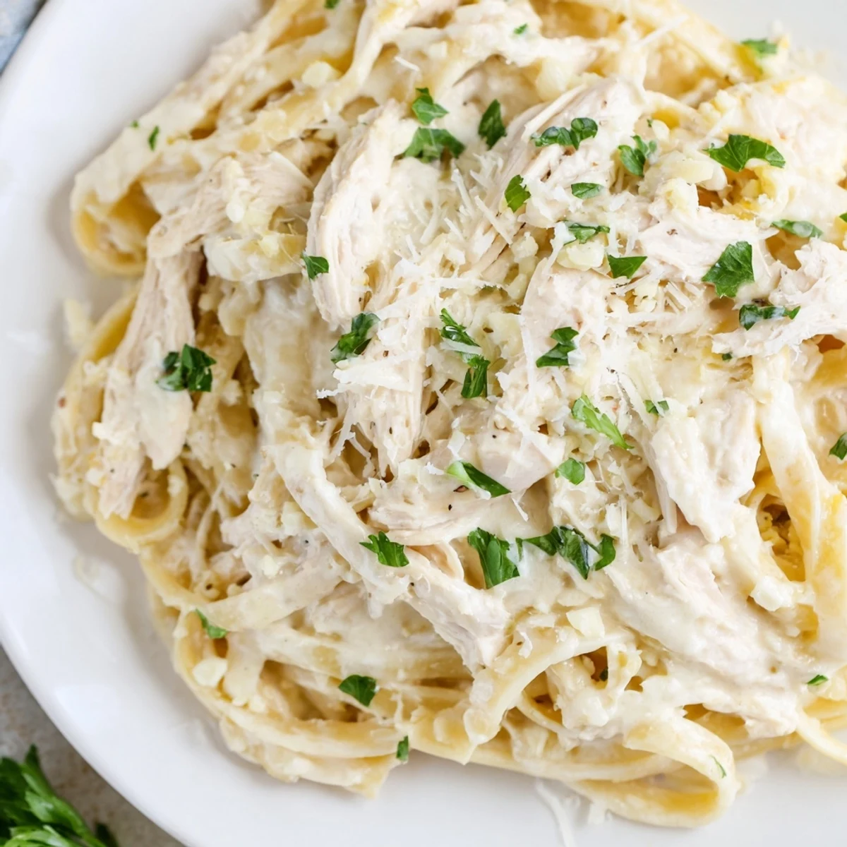 Homemade chicken Alfredo made in the crock pot featuring golden fettuccine noodles coated in a velvety white cream sauce