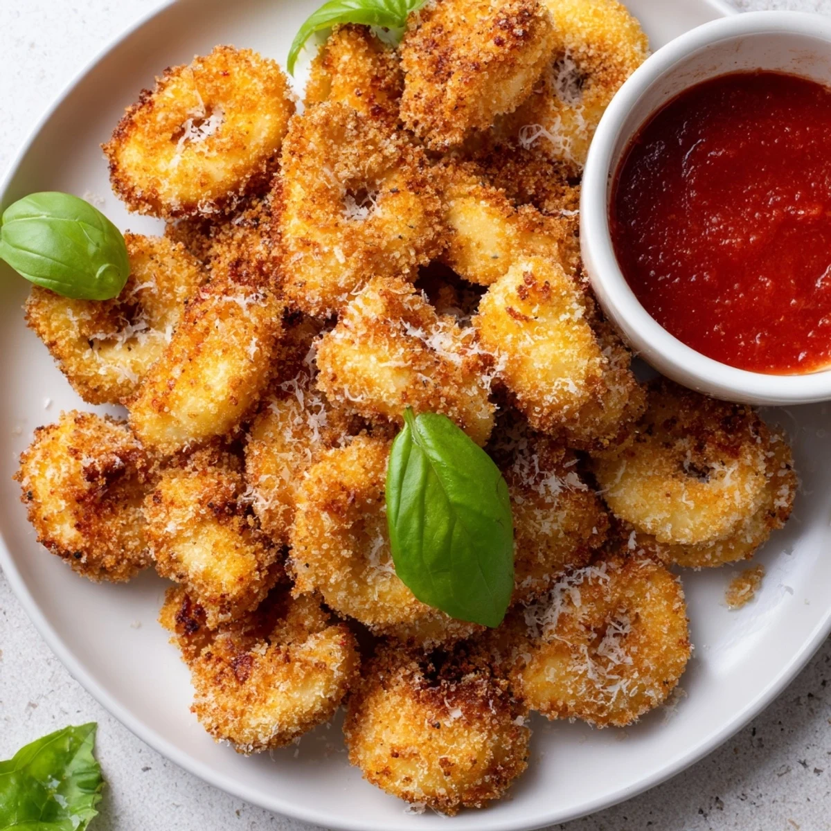 Italian appetizer of parmesan crusted tortellini cooked in air fryer basket with fresh basil garnish