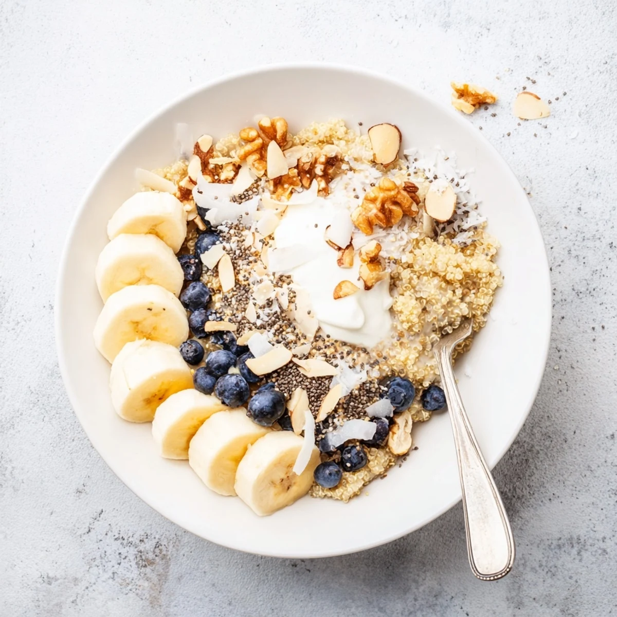 Creamy blueberry quinoa breakfast bowl topped with fresh berries, sliced banana and crunchy almonds