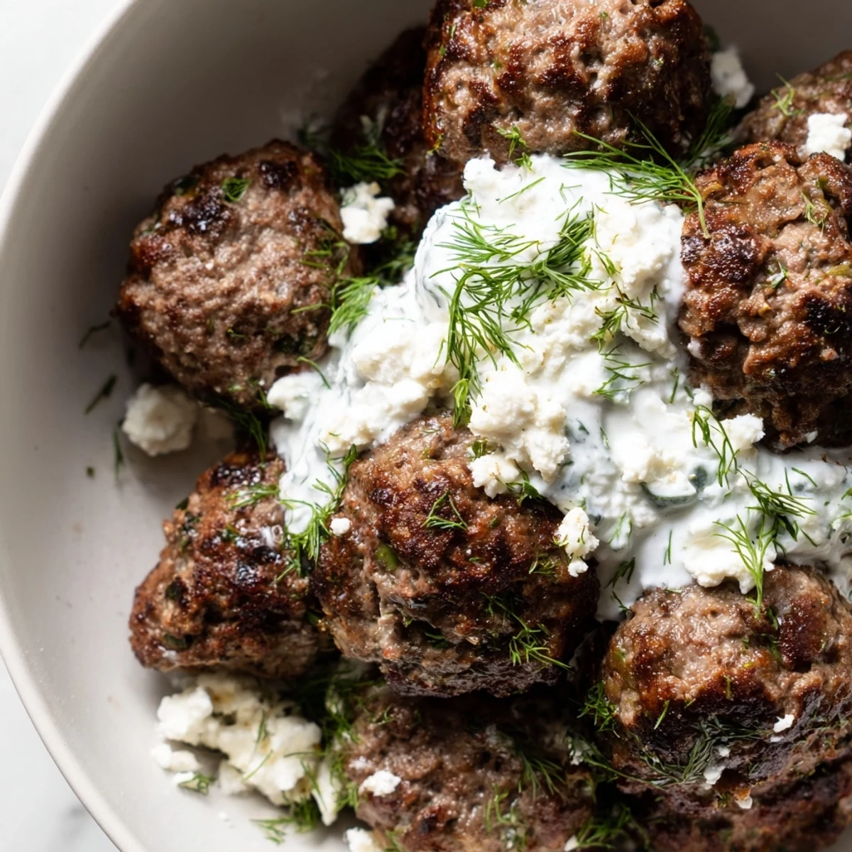 Mediterranean Greek meatball bowl drizzled with tzatziki alongside Kalamata olives and lemon