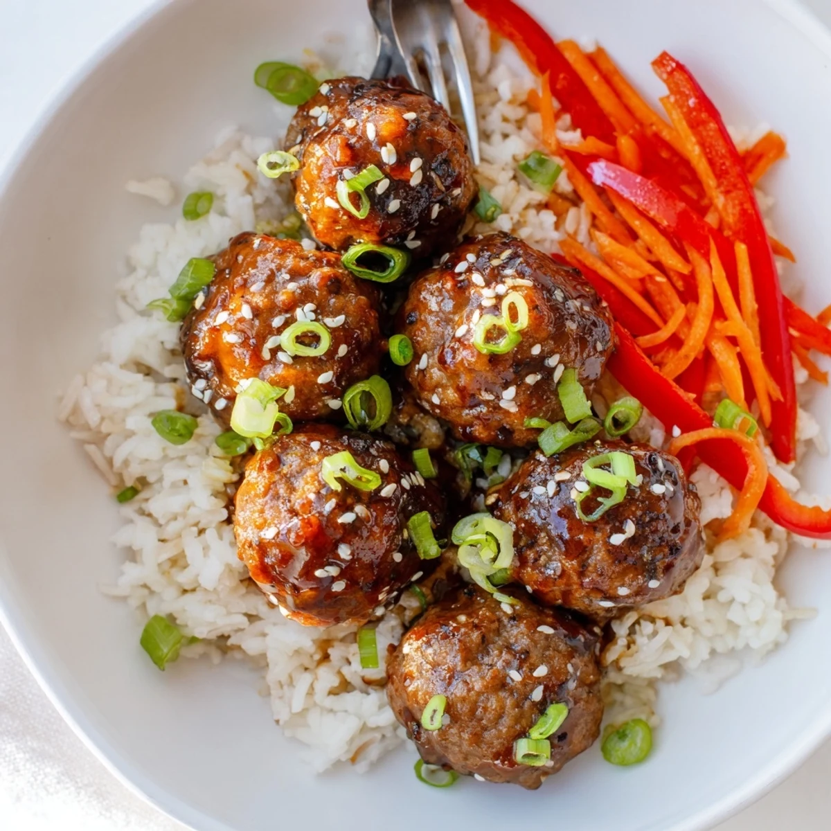 Plated Hello Fresh Firecracker Meatballs beside fluffy rice, sesame seeds, scallion garnish.