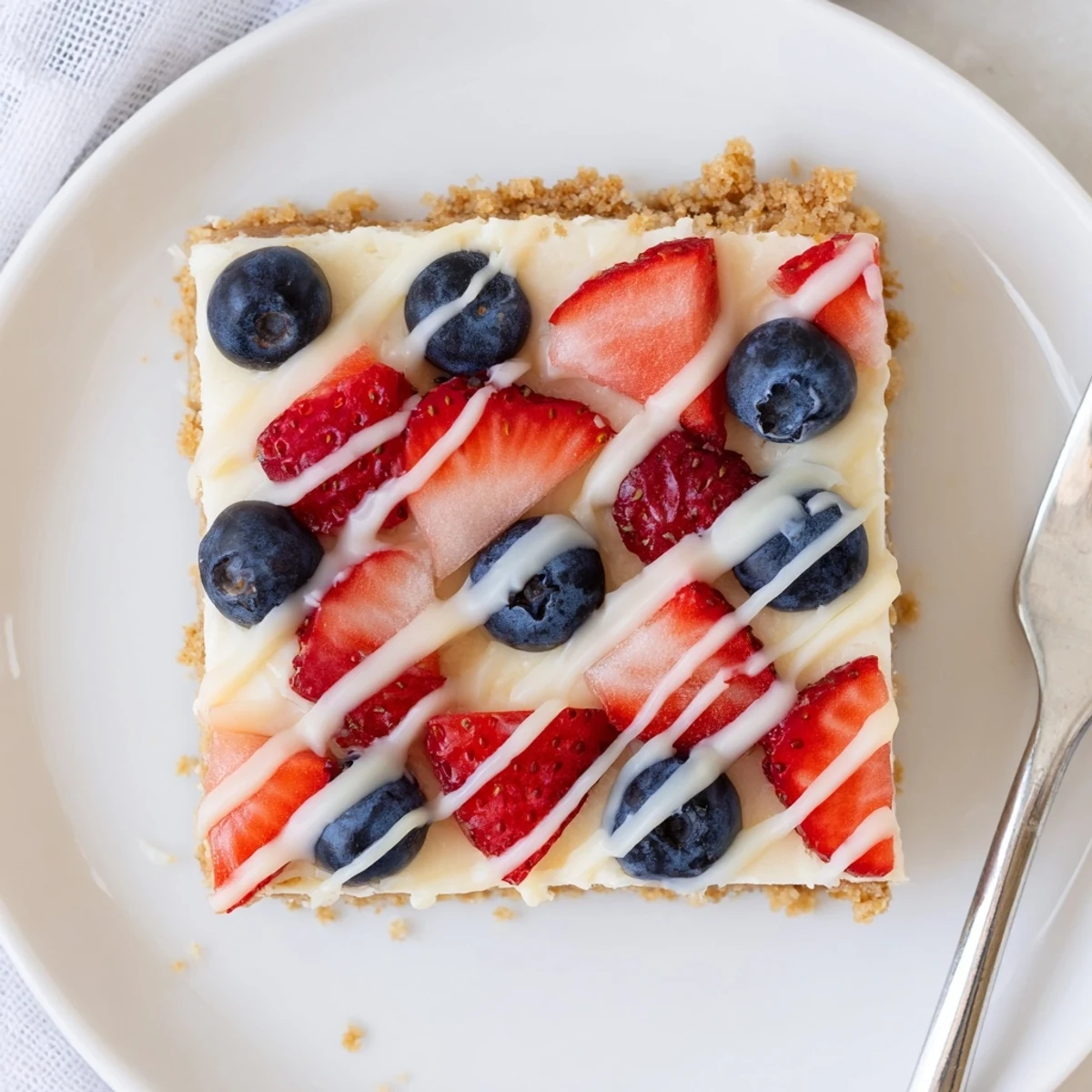 Sliced Patriotic Cheesecake Bars chilled, dotted with strawberries and blueberries for celebrations.