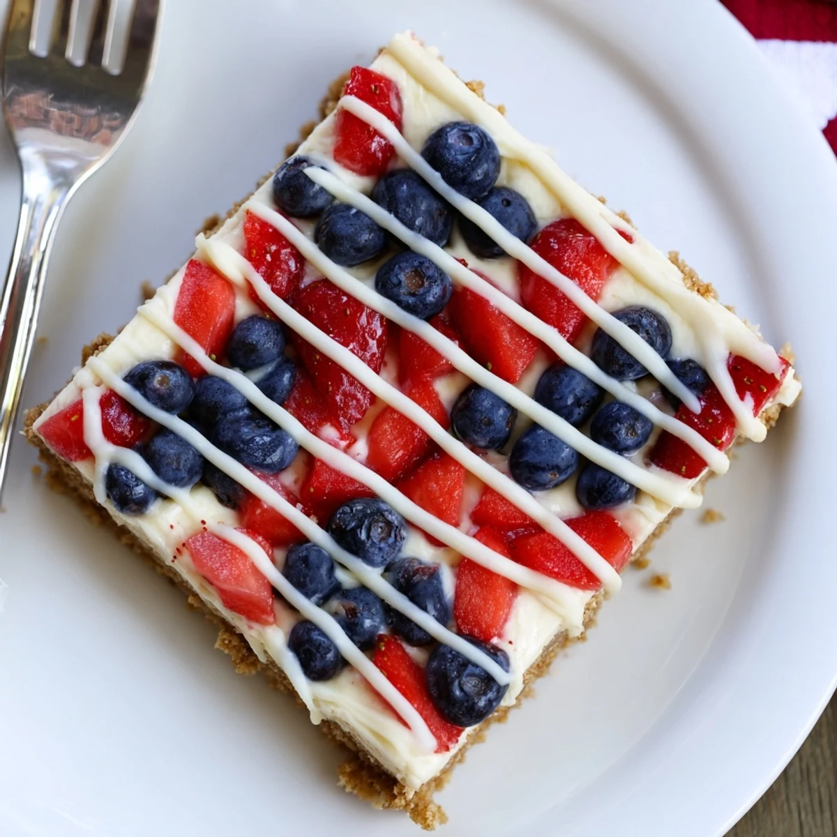 Patriotic Cheesecake Bars with creamy filling, buttery graham crust, fresh berry topping.