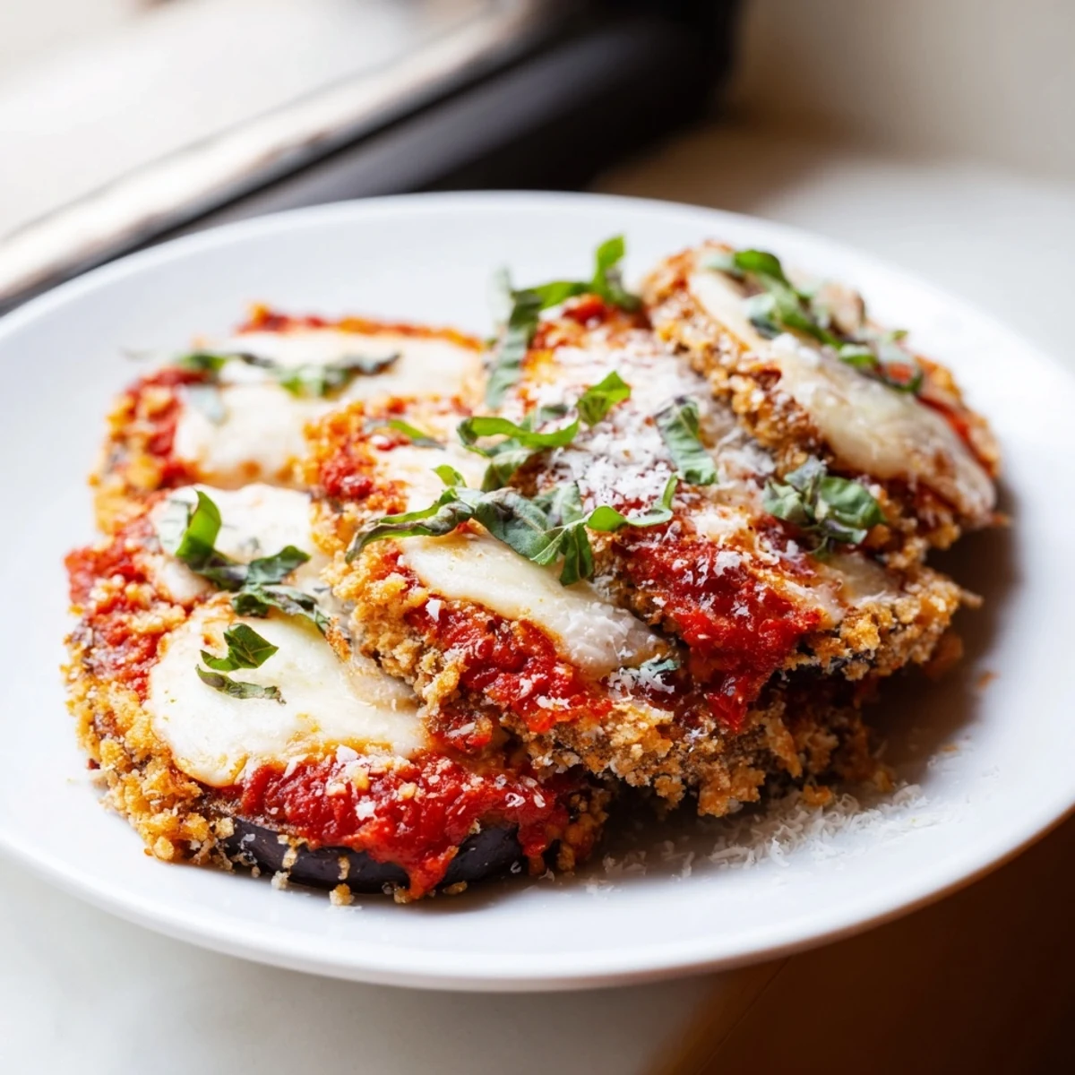 Golden baked eggplant parmesan layered with marinara and bubbling melted mozzarella cheese in a casserole dish