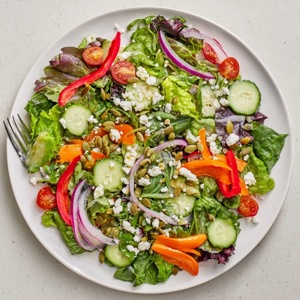 Colorful garden salad featuring shredded carrots, bell peppers, and leafy greens tossed in olive oil vinaigrette for a refreshing vegetarian meal