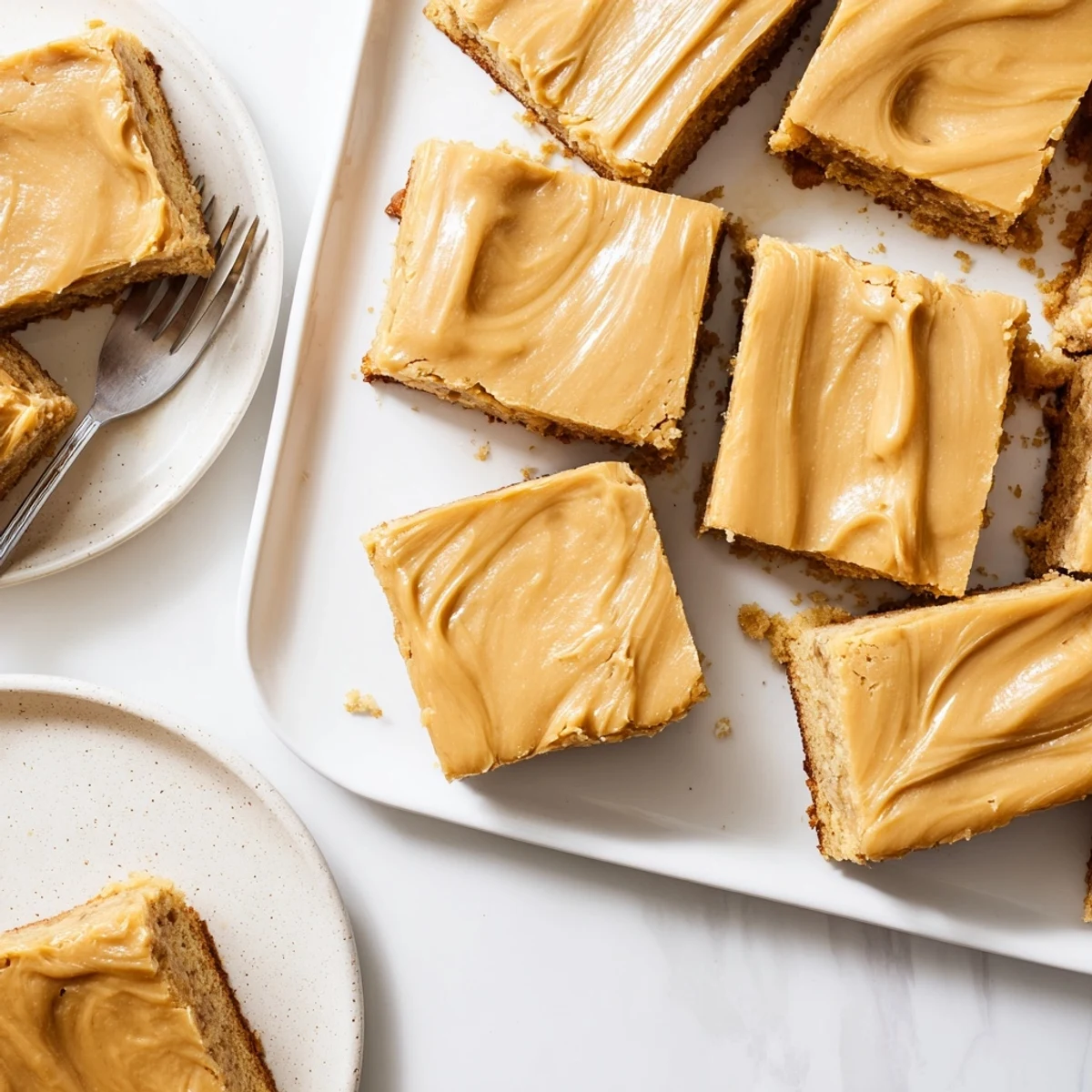 Banana bread brownies with brown butter frosting displayed on a rustic wooden cutting board, showing thick fudgy squares topped with creamy golden brown butter swirls