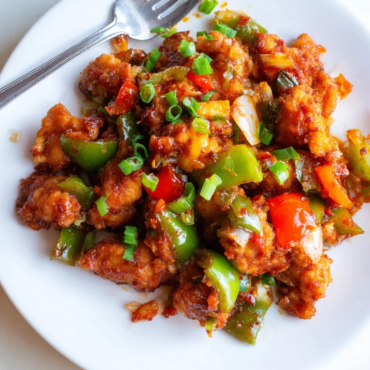 Crispy Chilli Chicken Indo Chinese tossed with peppers and scallions, steaming.