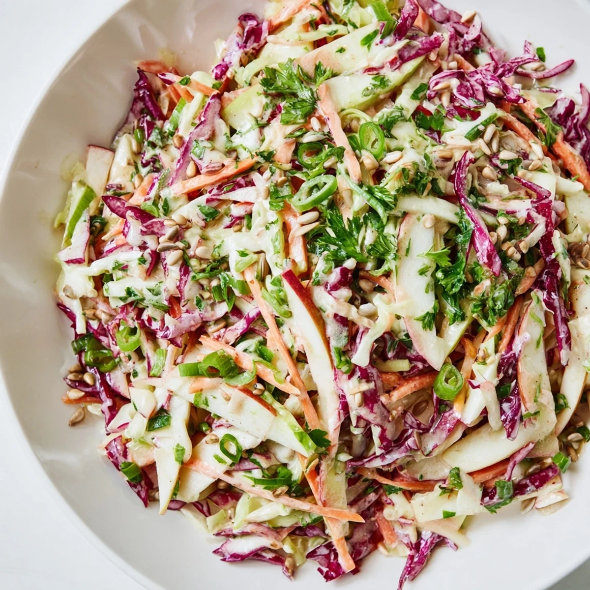 Colorful bowl of apple coleslaw featuring julienned apples and shredded carrot for added crunch